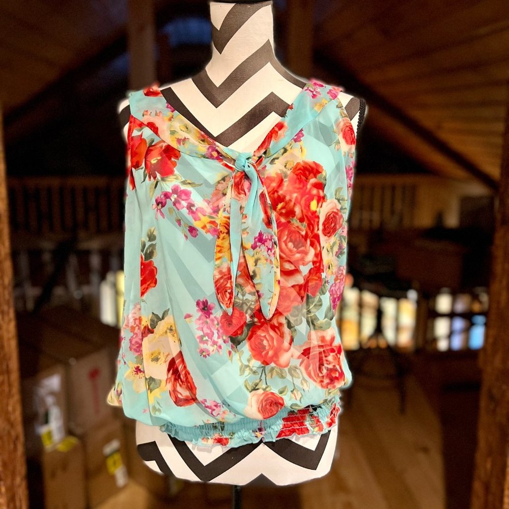 Beautiful sheer light sleeveless blouse with floral pattern on blue background